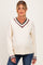 woman wearing a cream v-neck maternity sweater with maroon and navy stripes at the neckline and cuffs