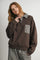 woman wearing a brown oversized sweatshirt with checked collar and pocket, styled with matching pants