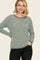 woman wearing a green and white striped long sleeve sweater with a round neckline and contrasting cuffs