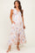woman wearing a floral maternity maxi dress with short flutter sleeves and pockets, standing and smiling
