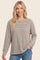 woman wearing a beige and brown striped long sleeve top with side slits and relaxed fit, smiling at the camera