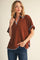 woman wearing a brown short sleeve top with blue trim and a v-neckline, paired with dark jeans