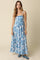 woman wearing a blue and white floral maxi dress with thin straps and a flared skirt