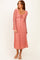 woman wearing a pink floral long sleeve midi dress with a tie detail at the neckline and a flowing skirt