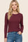woman wearing a burgundy long sleeve ribbed top with a round neckline, paired with blue jeans