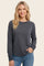 woman wearing a dark gray long sleeve sweatshirt with a rounded hem and gray ribbed cuffs, smiling at the camera