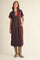 woman wearing a brown midi dress with a collar and striped details, paired with tan cowboy boots and standing with hands in pockets