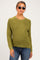 woman wearing a green knit maternity sweater and blue jeans, with a baby bump visible and sunglasses on