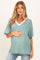 woman wearing a green striped maternity top with a v-neck and pocket, highlighting her baby bump