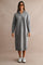 woman wearing a gray long sleeve knit zip-up dress with a collar and standing in sporty sneakers