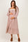 woman wearing a brown and cream checkered maternity dress with puff sleeves and a tiered skirt, holding her baby bump