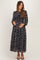 woman wearing a navy floral maternity maxi dress with long sleeves and a tied neckline, holding her baby bump