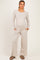 woman wearing a light taupe maternity loungewear set with a long sleeve henley top and wide-leg pants, baby bump visible