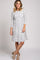 woman wearing a white and black striped long sleeve babydoll dress with tan peep toe booties