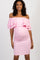 woman wearing a light pink off-shoulder maternity dress, cradling her baby bump at a celebration event