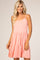 woman wearing a light pink spaghetti strap dress with a tiered, flared skirt