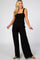 woman wearing a black maternity jumpsuit with wide legs and smocked bodice, showcasing her baby bump