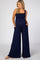 woman wearing a navy blue maternity jumpsuit with smocked bodice and side pockets, showcasing her baby bump