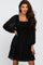 woman wearing a black puff sleeve mini dress with textured dots and a square neckline