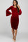 woman wearing a red velvet maternity dress with bell sleeves and side ruching, showing her baby bump