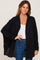 woman wearing a black oversized button-up shirt over a white tank top and blue jeans
