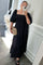 woman wearing a black smocked puff sleeve midi dress and holding a tan woven clutch bag