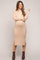 woman wearing a beige ribbed maternity sweater dress with side slits, showcasing her baby bump and paired with ankle boots