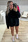 woman wearing a black oversized sweatshirt and shorts, smiling in a mirror selfie with pink sneakers