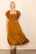 woman wearing a mustard yellow midi dress with ruffled sleeves and a smocked bodice