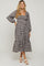 woman wearing a black and white gingham maternity dress with long sleeves and ruffle hem, showcasing her baby bump