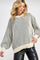 woman wearing a cream striped oversized knit sweater with balloon sleeves and a relaxed fit, paired with black leather pants
