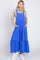 woman wearing a long blue tiered maxi dress with pockets and adjustable straps, styled with a beige turtleneck and white sneakers