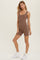 woman wearing a brown ribbed bodysuit with short legs and white sneakers