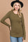 woman wearing an olive green ribbed long sleeve top with a scoop neckline and side slits, styled with a black hat