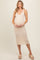 woman wearing a beige ribbed maternity dress, cradling her baby bump