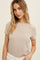 woman wearing a light beige short sleeve top with a round neckline