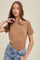 woman wearing a brown ribbed short sleeve t-shirt paired with high-waisted denim shorts
