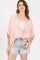woman wearing a coral and white striped oversized button-up shirt with rolled sleeves and distressed denim shorts