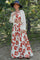 woman wearing a white floral maxi skirt and matching crop top with a knitted cardigan and wide-brimmed hat