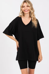 woman wearing a loose black oversized v-neck t-shirt with short sleeves, paired with black bike shorts