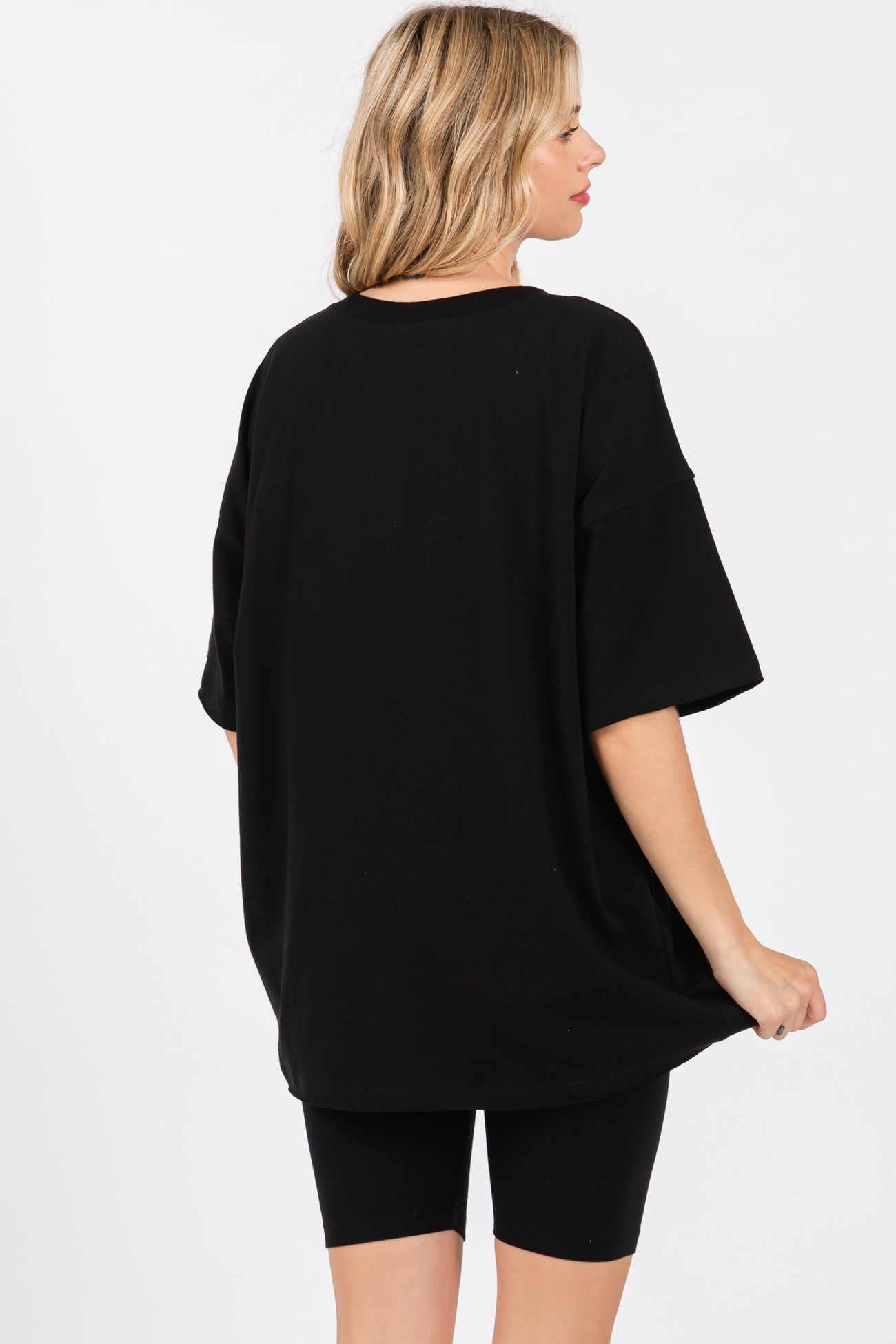 woman wearing an oversized black t-shirt with short sleeves and black bike shorts, showing the back view