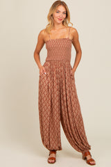 woman wearing a brown patterned jumpsuit with adjustable straps and pockets, styled with brown sandals