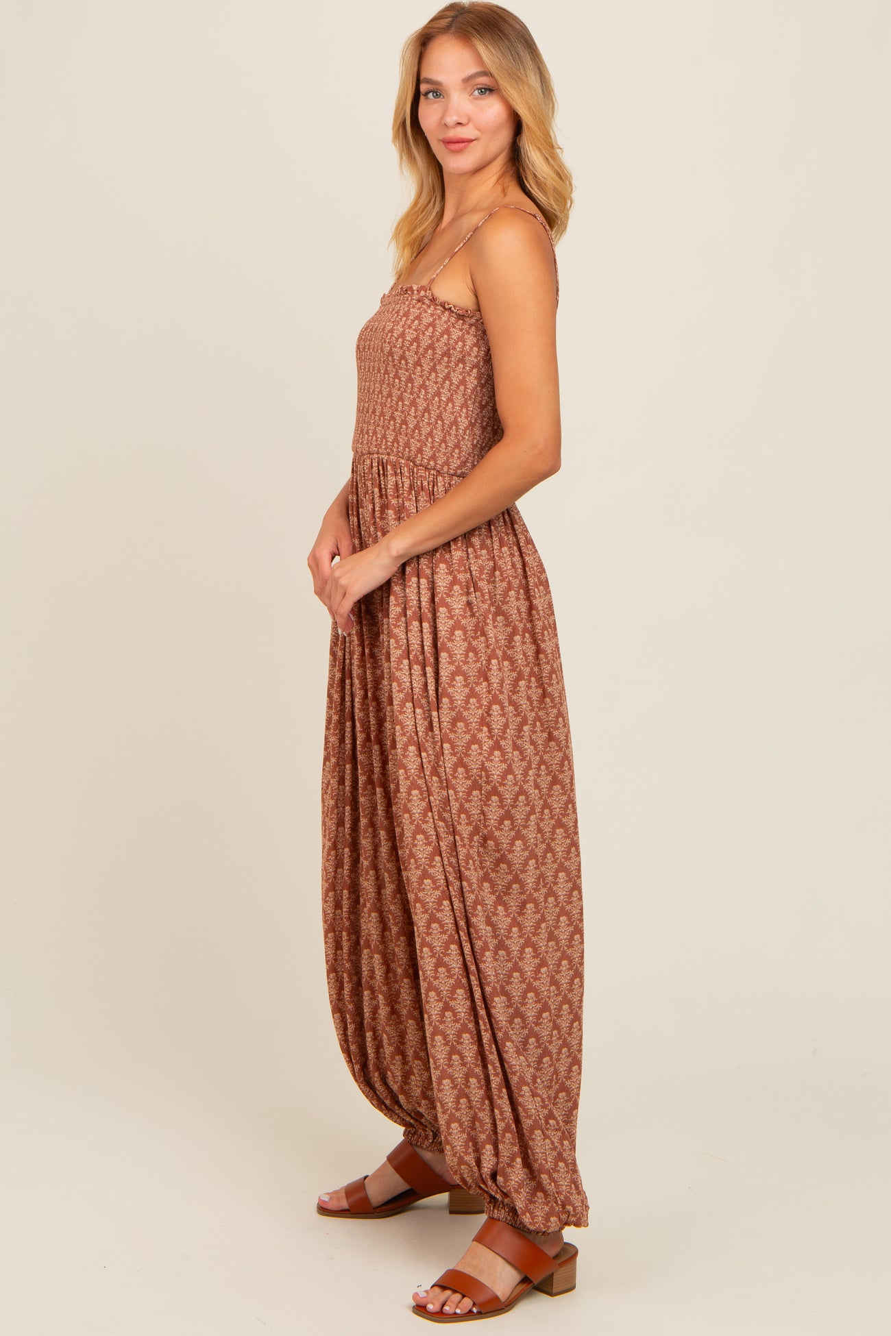 woman wearing a brown patterned maxi dress with a smocked bodice and relaxed fit, paired with brown sandals