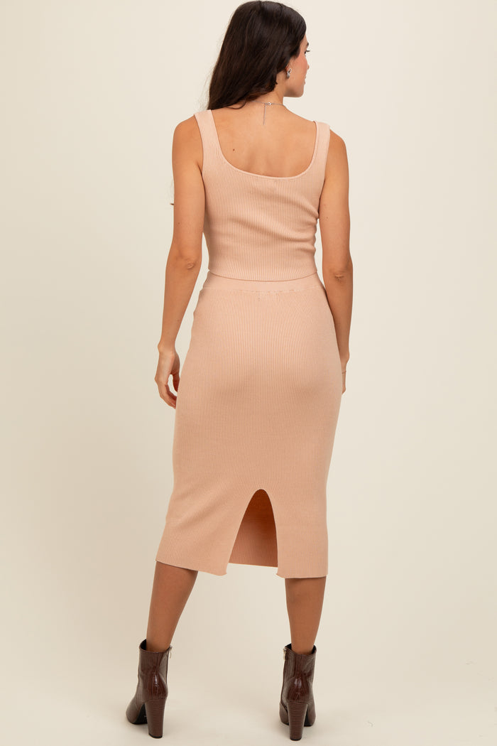 woman wearing a fitted light pink ribbed midi dress with a side slit and a scoop neckline