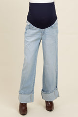 light blue maternity jeans with a dark blue over-the-bump waistband and rolled cuffs, styled with brown heeled boots