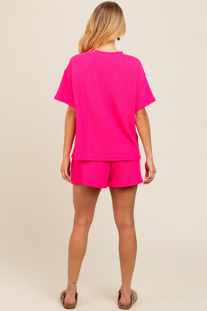woman wearing a bright pink ribbed t-shirt and matching shorts, viewed from the back