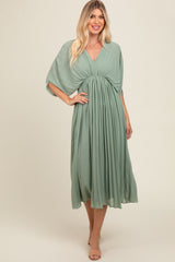 woman wearing a flowy sage green midi dress with a wrap-style top and gathered waist