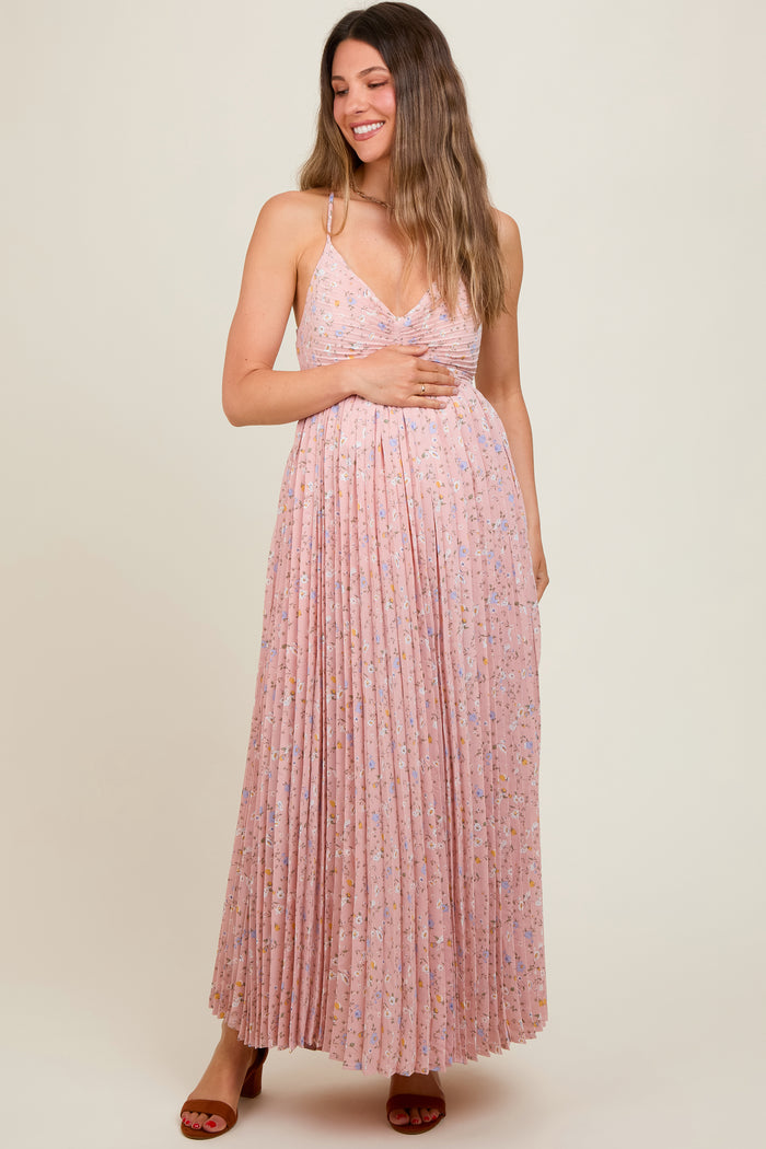 woman wearing a light pink floral maternity maxi dress with pleated detailing and a v-neckline