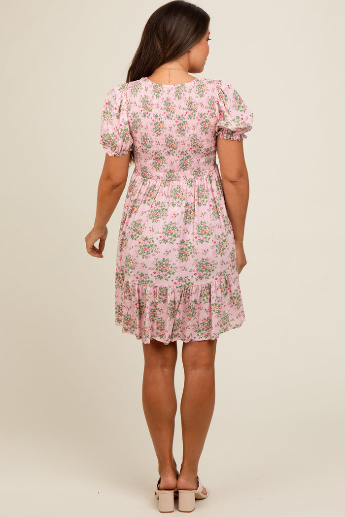 woman wearing a floral pink maternity dress with puff sleeves and a tiered hem, showcasing her baby bump from behind