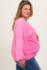 woman wearing a bright pink maternity sweatshirt with a relaxed fit and visible baby bump